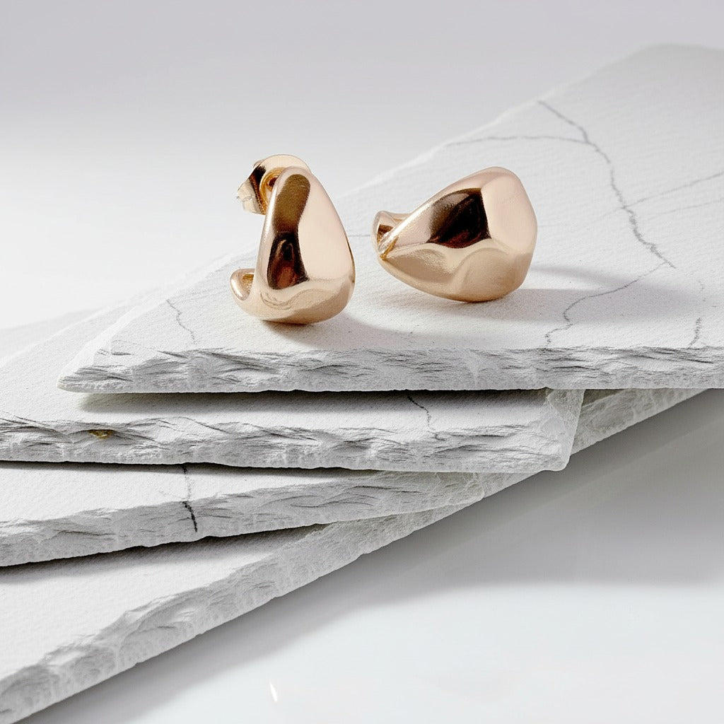 Gold swan-shaped earrings on a marble surface