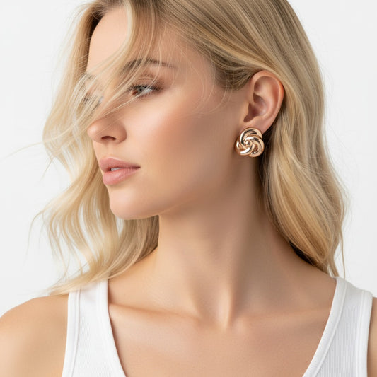 Woman wearing gold earrings with a plain background