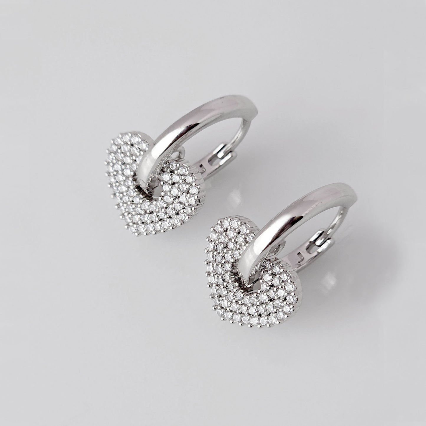 Crafted from low maintenance and hypoallergenic stainless steel, these Small Silver Sparkle Hearts Hoop Earrings boast a tarnish-proof design that is both sustainable and lightweight. Enjoy high-quality, luxurious style without any worries of skin irritation.