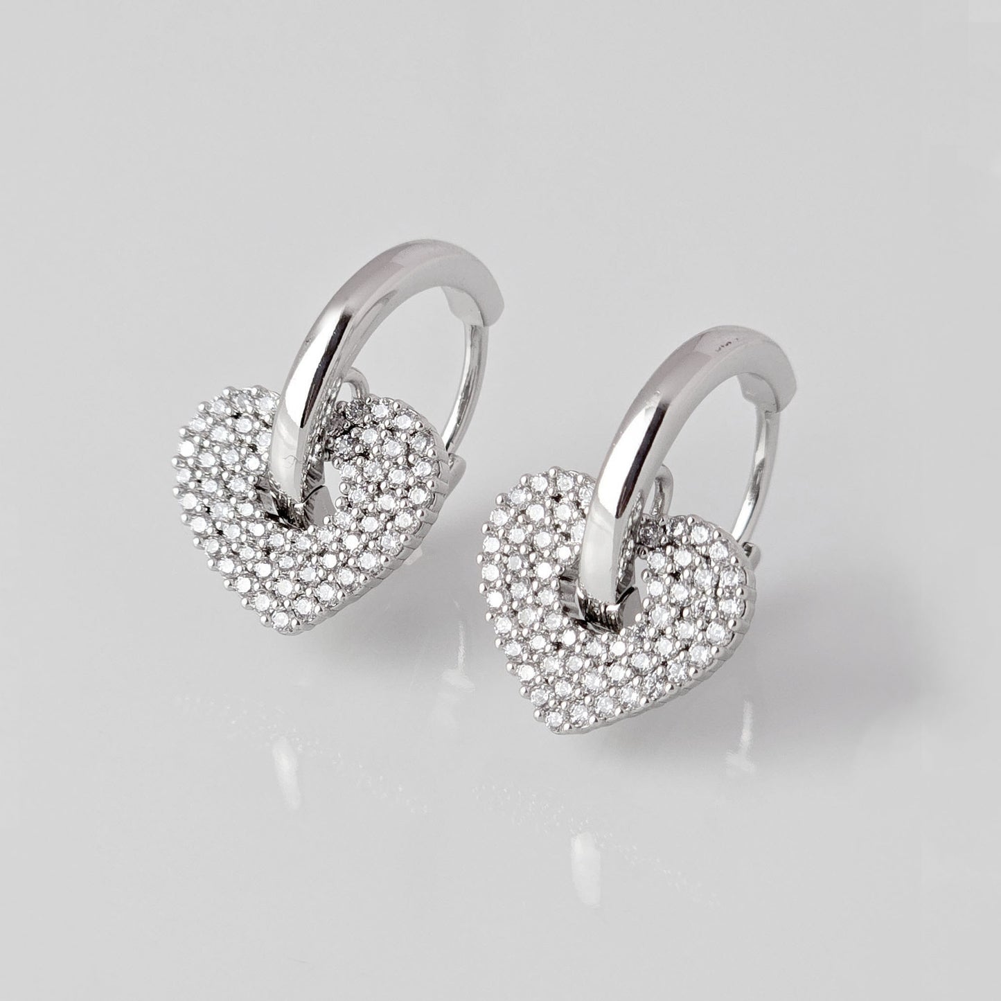 Crafted from low maintenance and hypoallergenic stainless steel, these Small Silver Sparkle Hearts Hoop Earrings boast a tarnish-proof design that is both sustainable and lightweight. Enjoy high-quality, luxurious style without any worries of skin irritation.