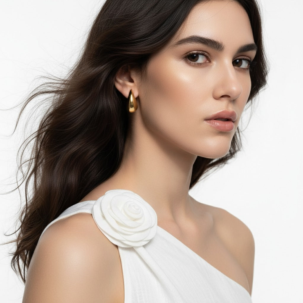 Woman wearing a white garment with a floral detail on a plain background
