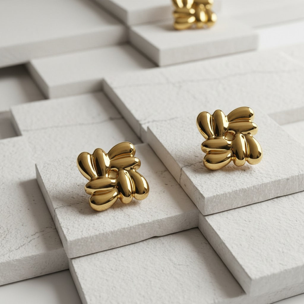 Gold knot earrings on a light stone surface