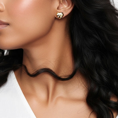Close-up of a woman wearing gold heart-shaped earrings with a neutral background