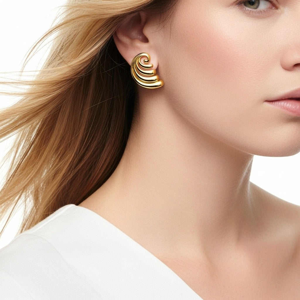 Close-up of a woman wearing gold earrings with a plain background