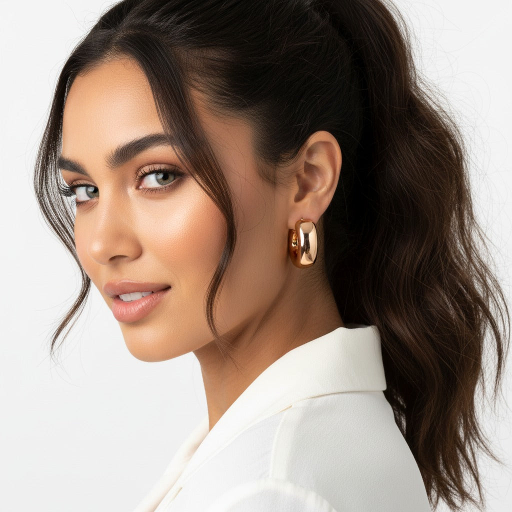 Woman with a stylish ponytail wearing gold earrings against a neutral background