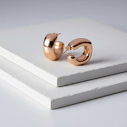 Rose gold hoop earrings on a light gray surface