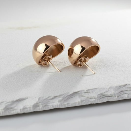 Rose gold sphere earrings on a light marble surface