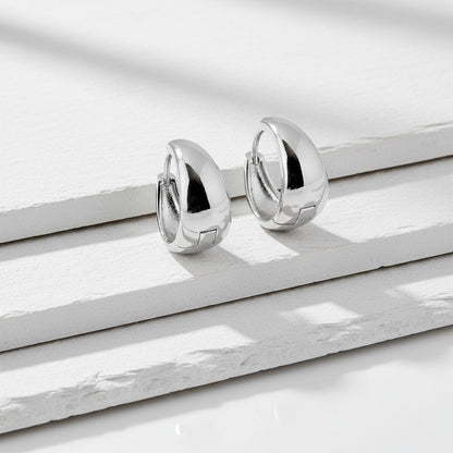 Pair of silver hoop earrings on a white marble surface