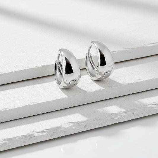 Pair of silver hoop earrings on a white marble surface
