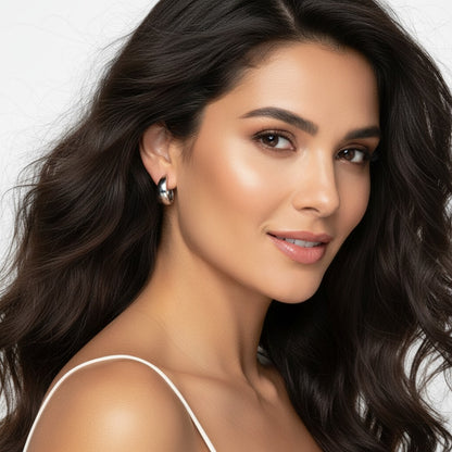 Woman with long dark hair wearing a white top against a neutral background
