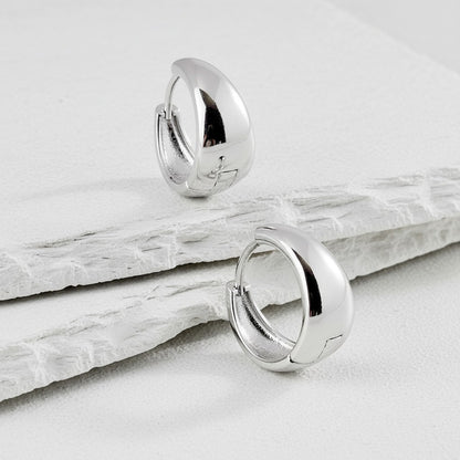 Silver hoop earrings on a light gray surface
