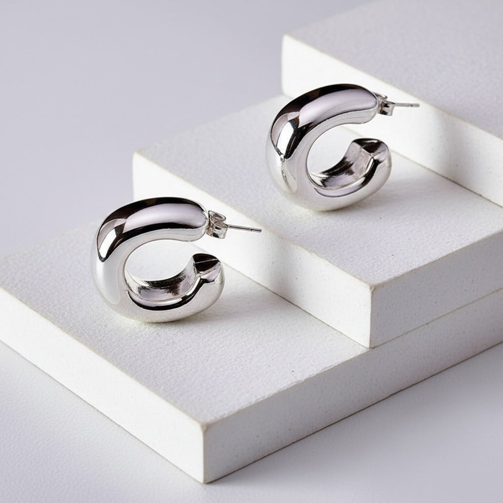 Silver hoop earrings on a white geometric platform