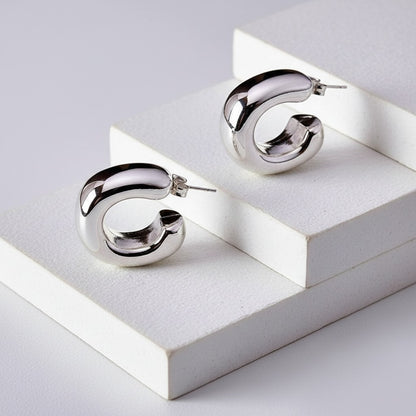 Silver hoop earrings on a white geometric platform