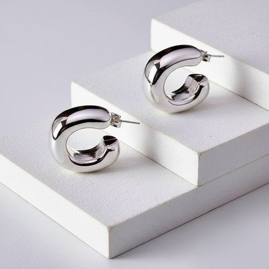 Silver hoop earrings on a white geometric platform