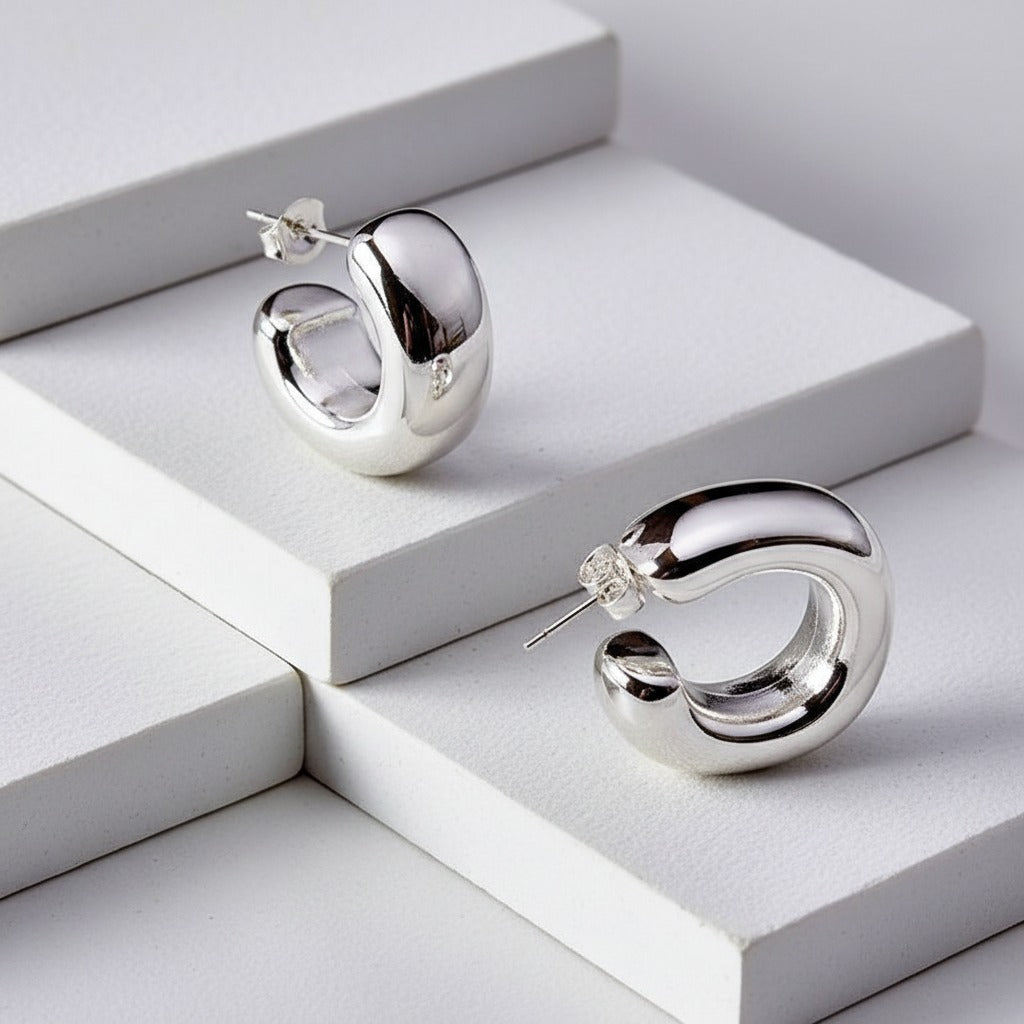 Silver hoop earrings on a white geometric background