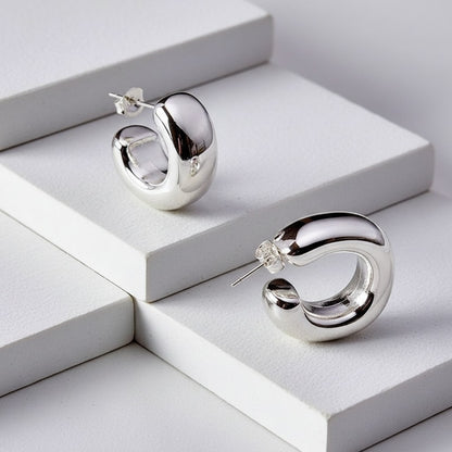 Silver hoop earrings on a white geometric background