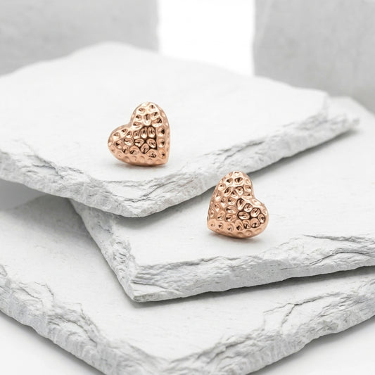 Rose gold heart-shaped earrings on a marble surface Medium Rose Gold Amora Heart Stud Earrings premium stainless steel hypoallergenic, waterproof, tarnish-proof, and lightweight