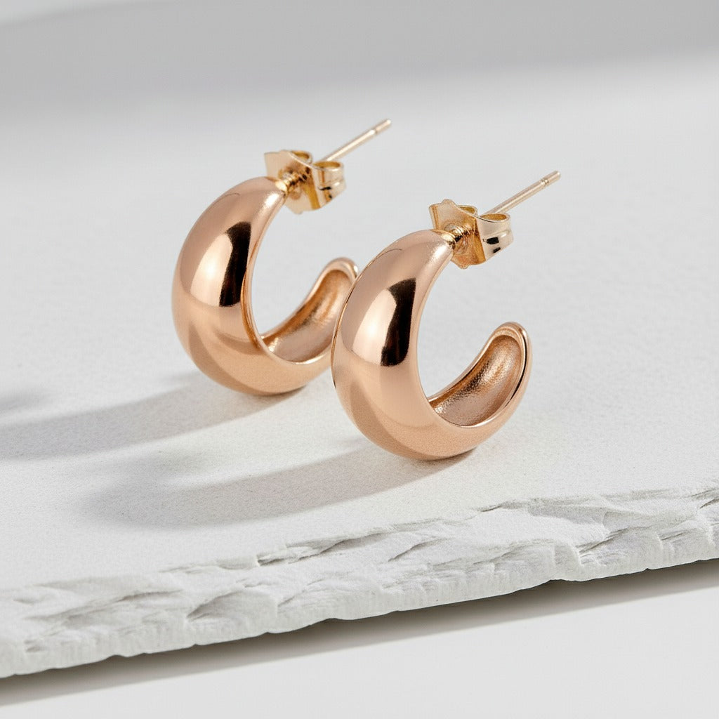 Rose gold hoop earrings on a marble surface