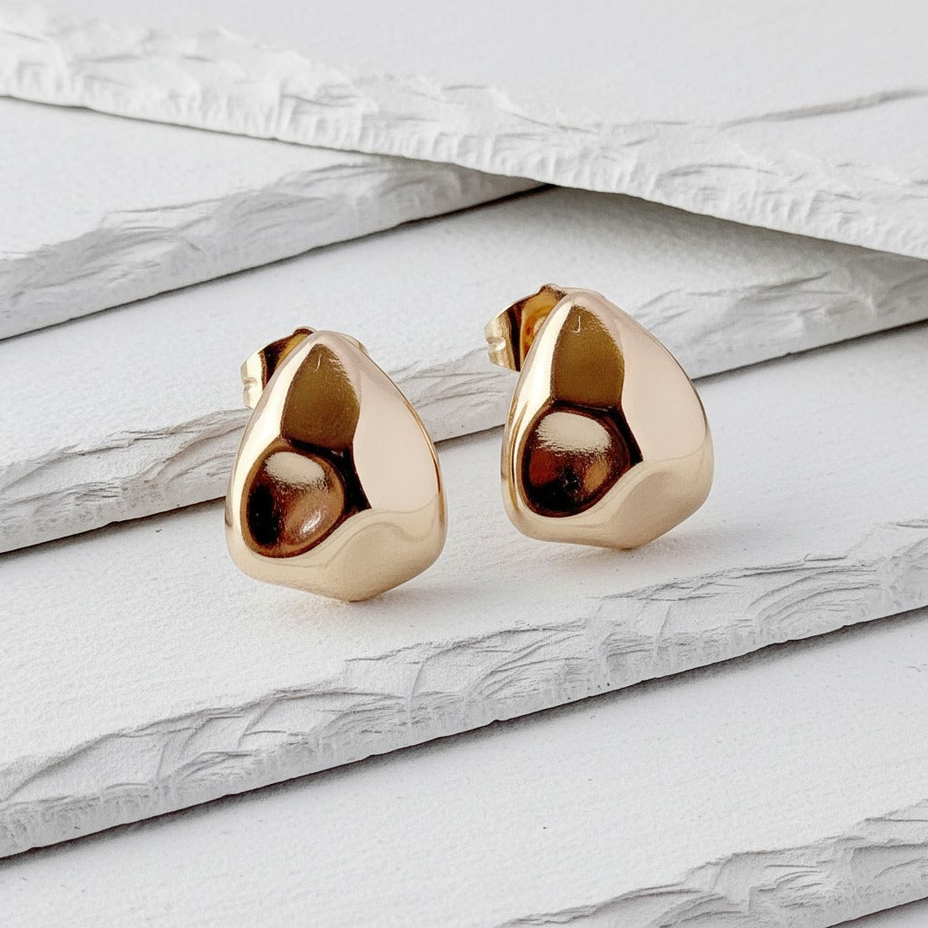Gold teardrop-shaped earrings on a marble surface