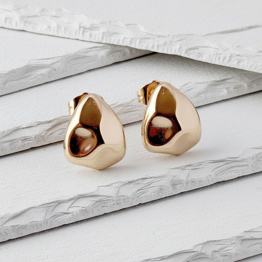 Gold teardrop-shaped earrings on a marble surface