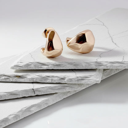 Gold swan-shaped earrings on a marble surface