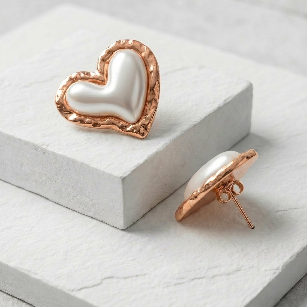 Heart-shaped earrings with rose gold frame and pearl center on a white Medium Rose Gold Coral Heart Stud Earrings premium stainless steel hypoallergenic, waterproof, tarnish-proof, and lightweight