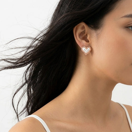 Close-up of a woman wearing a heart-shaped earring with a white background Medium Rose Gold Coral Heart Stud Earrings premium stainless steel hypoallergenic, waterproof, tarnish-proof, and lightweight 