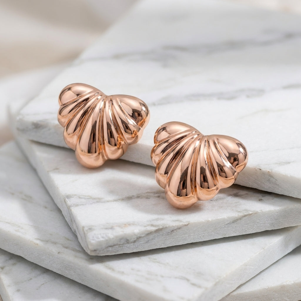 Rose gold shell-shaped earrings on a marble surface Medium Rose Gold Maré Heart Stud Earrings premium stainless steel hypoallergenic, waterproof, tarnish-proof, and lightweight