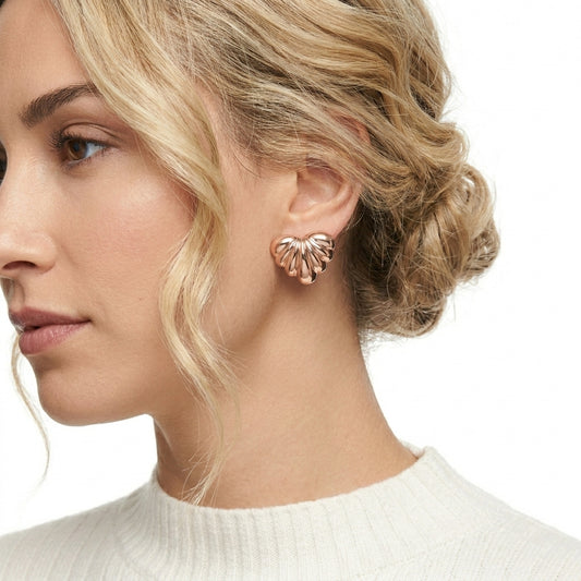 Close-up of a woman wearing rose gold heart-shaped earrings on a white background Medium Rose Gold Maré Heart Stud Earrings premium stainless steel hypoallergenic, waterproof, tarnish-proof, and lightweight