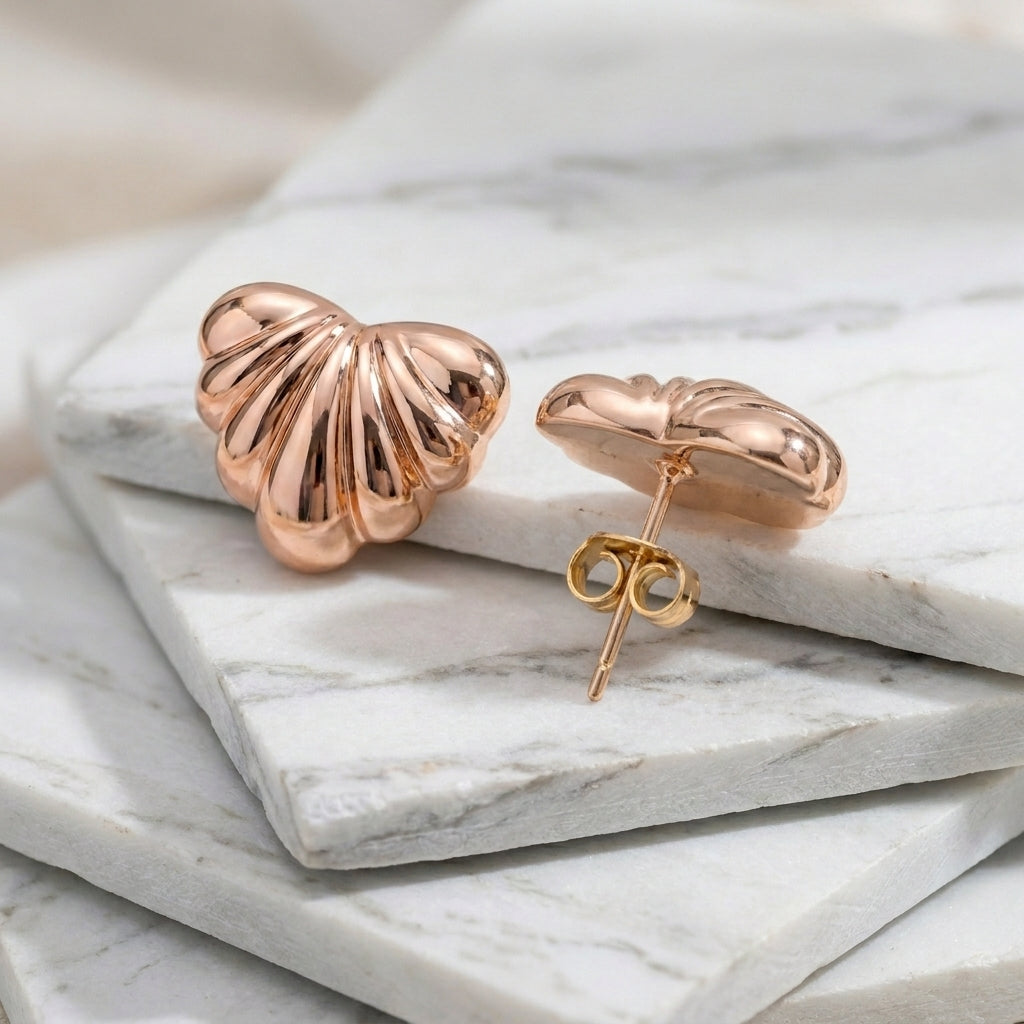 Rose gold shell-shaped earrings on a marble surface Medium Rose Gold Maré Heart Stud Earrings premium stainless steel hypoallergenic, waterproof, tarnish-proof, and lightweight