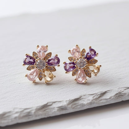 Pair of floral earrings with purple and pink gemstones on a light background