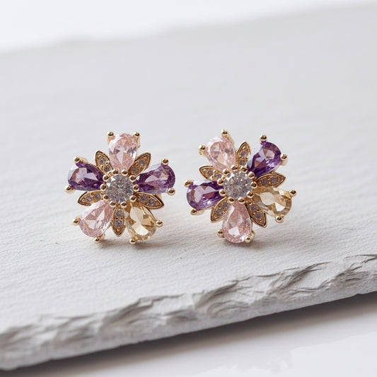 Pair of floral earrings with purple and pink gemstones on a light background