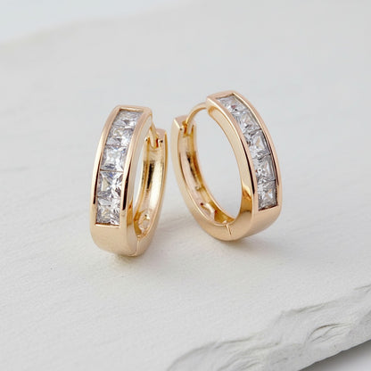 Gold hoop earrings with clear gemstones on a light gray background