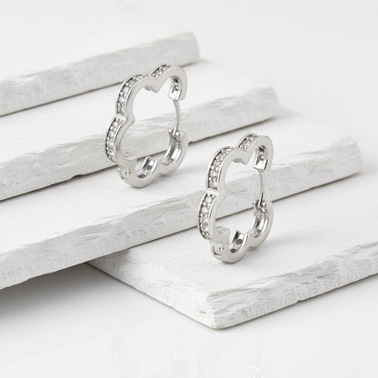 Pair of silver earrings on a white wooden surface