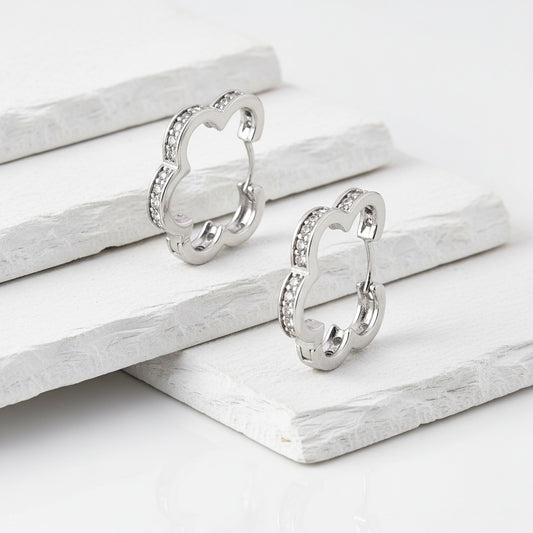 Pair of silver earrings on a white wooden surface