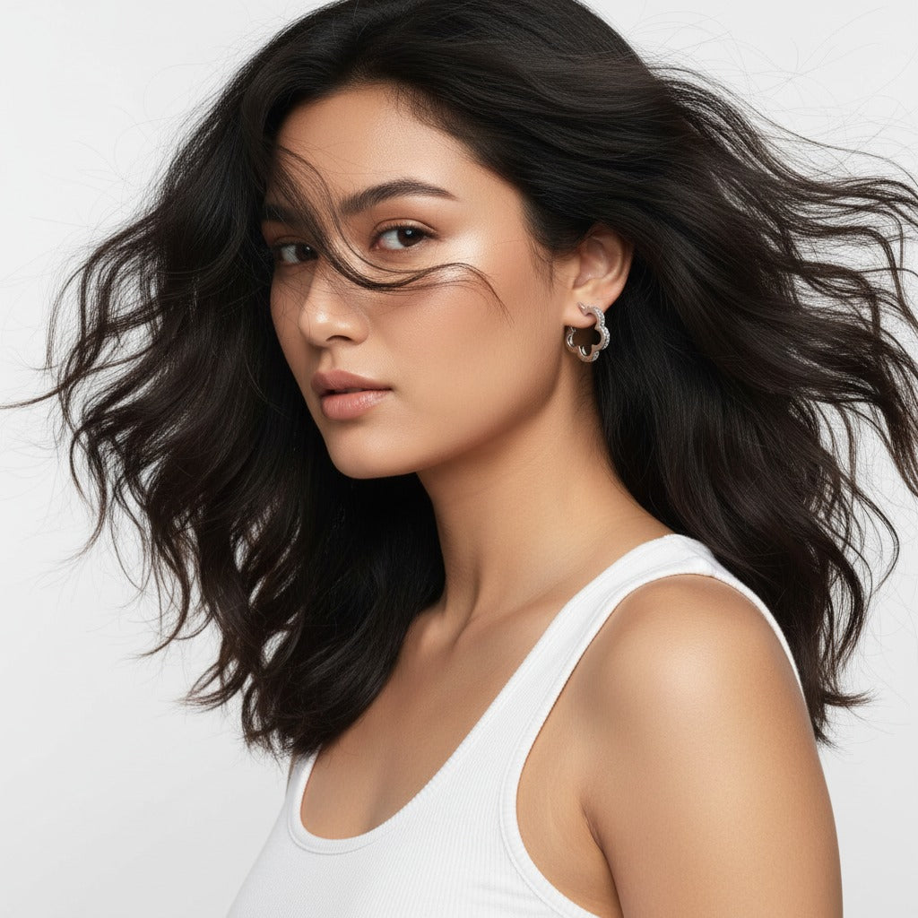 Woman with wavy black hair wearing a white tank top on a light gray background