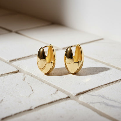 Gold hoop earrings on a light stone surface