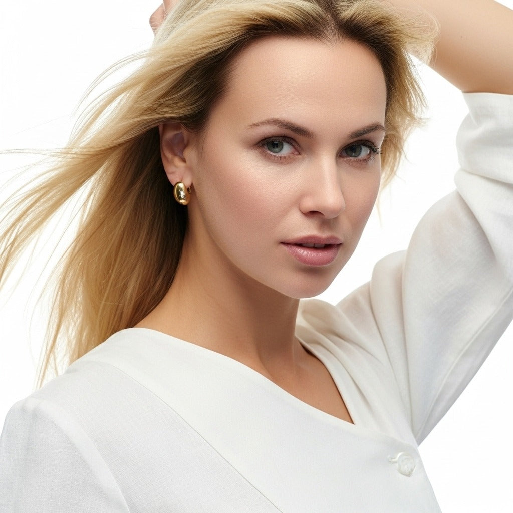 Woman with blonde hair wearing a white top against a light background