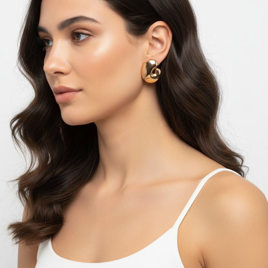 Woman wearing gold earrings with a plain background