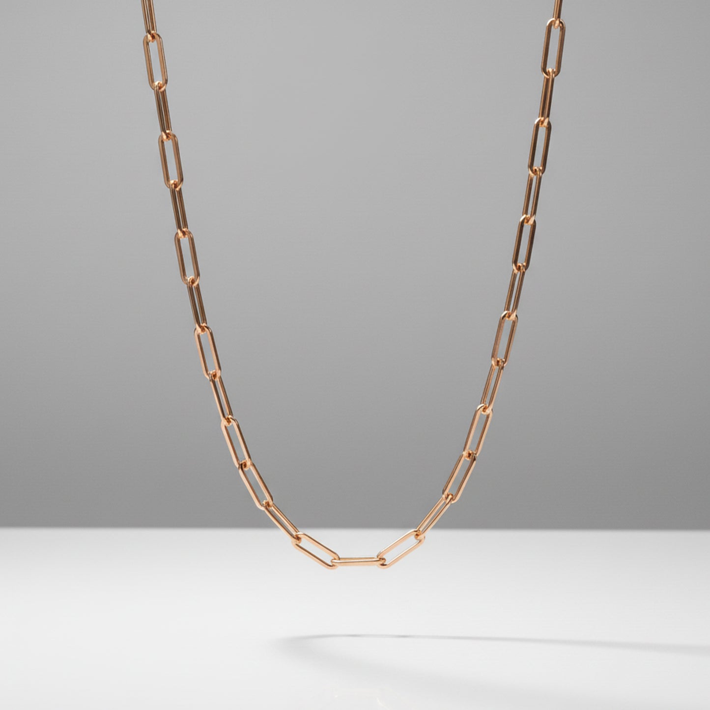 Rose gold chain necklace on a gray background