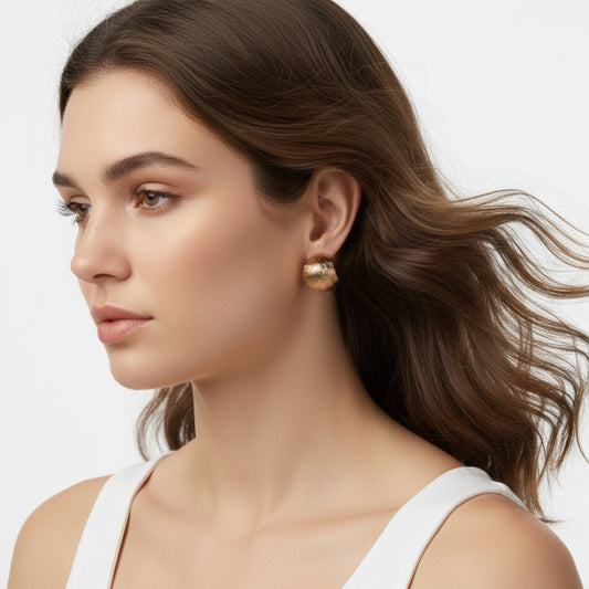 Woman wearing gold earrings with a neutral background