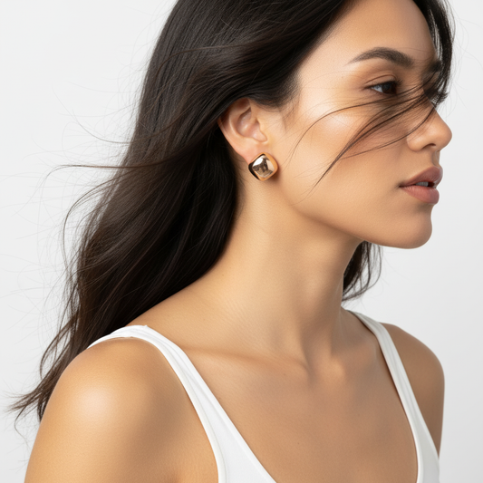 Woman wearing gold earrings with a plain background