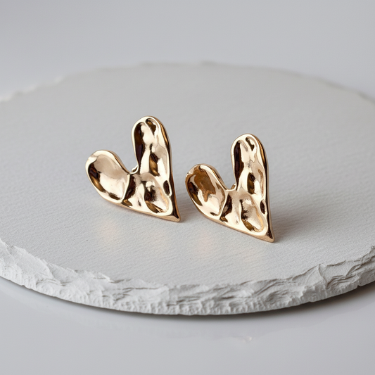 Gold heart-shaped earrings on a gray stone surface