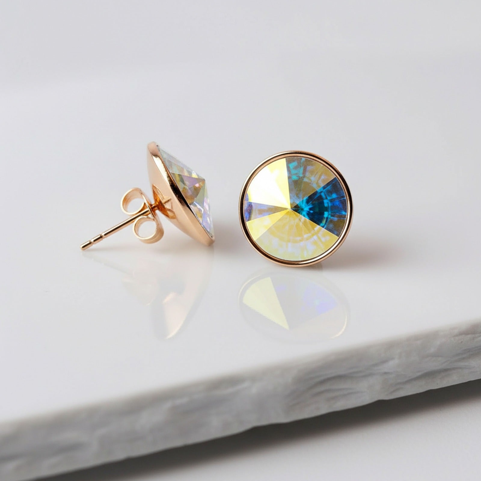 Gold earrings with colorful gemstones on a marble surface