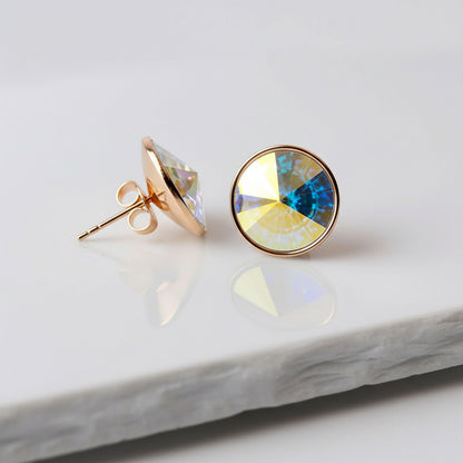 Gold earrings with colorful gemstones on a marble surface