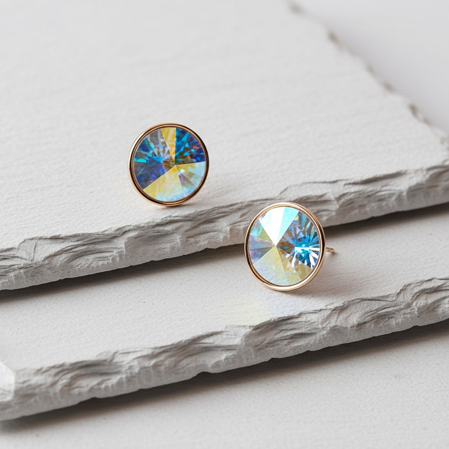 Round earrings with colorful gemstones on a marble surface