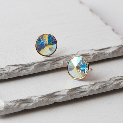 Round earrings with colorful gemstones on a marble surface