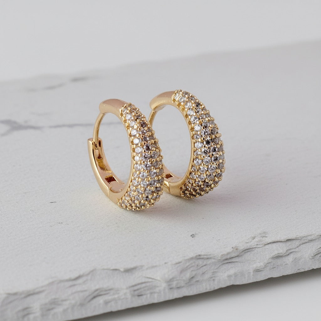 Gold hoop earrings with diamond accents on a marble surface