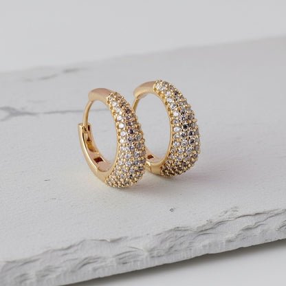 Gold hoop earrings with diamond accents on a marble surface