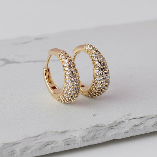 Gold hoop earrings with diamond accents on a marble surface